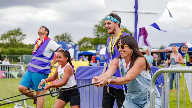 a mum and daughter at carfest having fun by playing a game pulling on a rope
