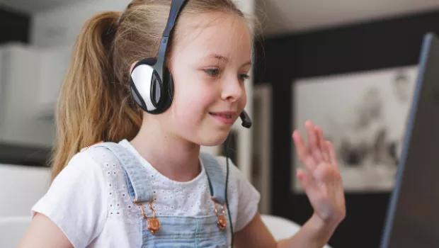 Young girl waving on a laptop for a video call