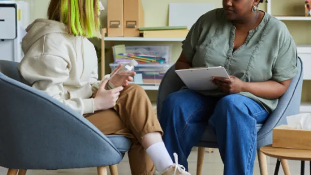 Health professional talks and supports young girl with vibrant hair.