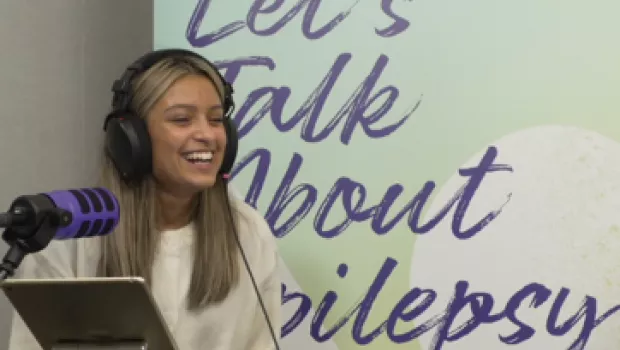 A young girl with headphones laughing on recording of podcast