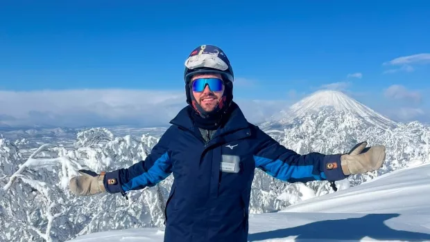 Miles, a man in a snowsuit, stands on a snow-capped mountaintop.