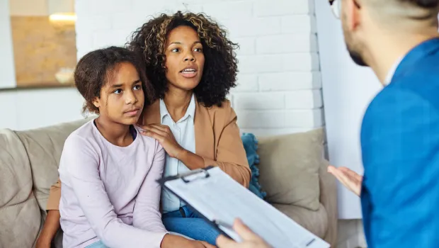 A doctor speaks to a mother and daughter about his notes.