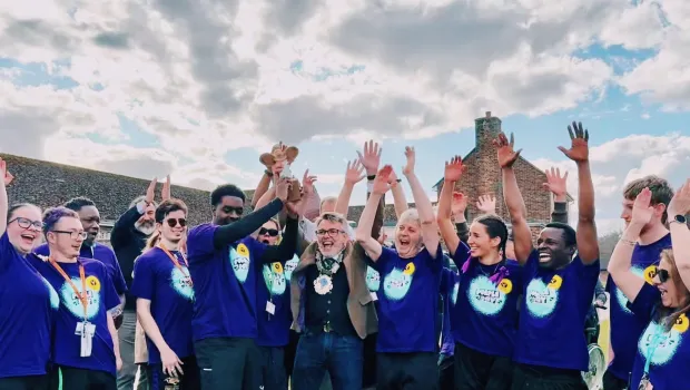 A group of colleagues in Purple Day t-shirts celebrate completing an event.