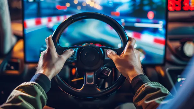 A driver on a simulator shows their hands on steering wheel.