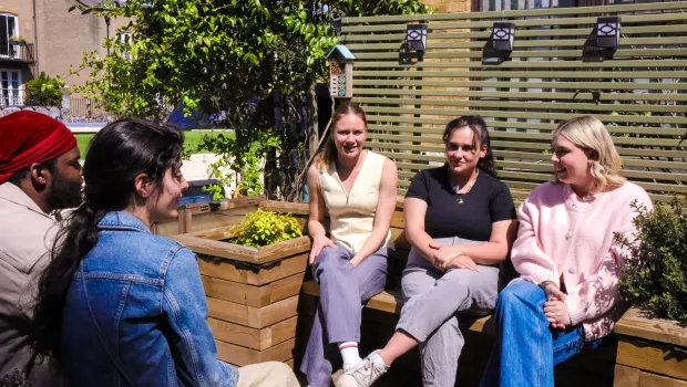 A group of young people chat on outdoor benches.