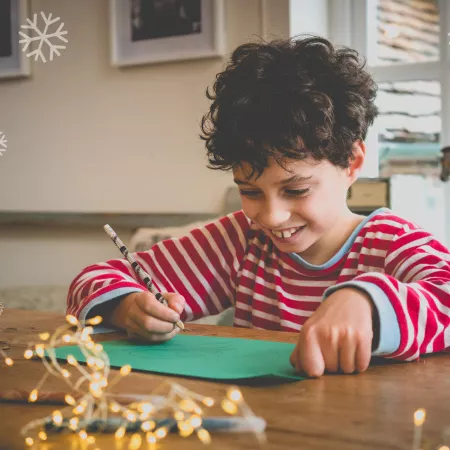 A young boy writes a Christmas list.