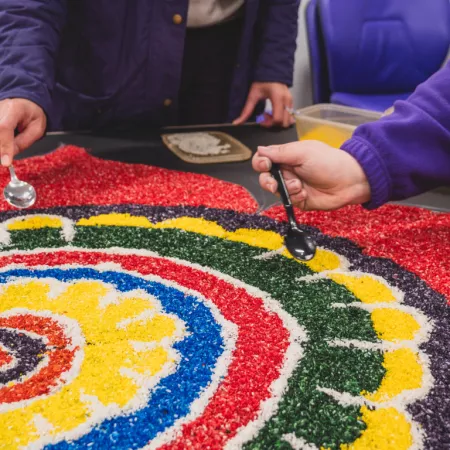 Two individuals spoon colourful stones onto a mural for the SHINE strategy.