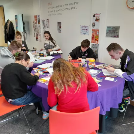 A group of young people from Young Epilepsy sit at a table putting together a pamphlet.