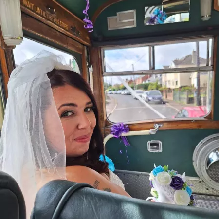 Laura, a young woman, smiles in a wedding dress from a vehicle.