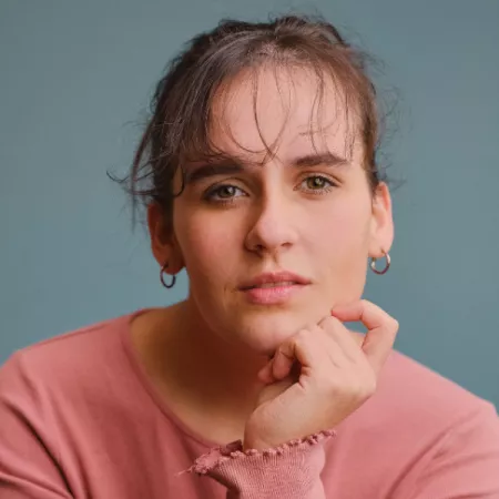 A young woman, Rebecca, looks thoughtfully off-camera.