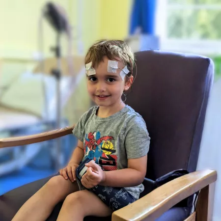 A young boy sits in a doctors office wearing an EEG.