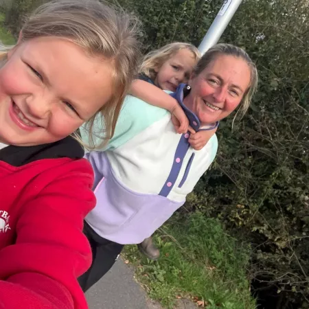 A woman and her two children smile in a selfie outdoors.