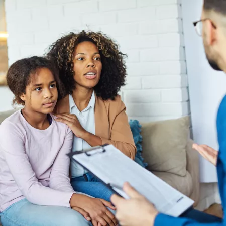 A doctor speaks to a mother and daughter about his notes.
