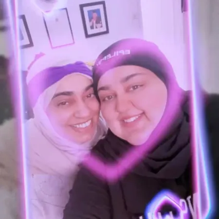 Two women in headscarves smile in a selfie.