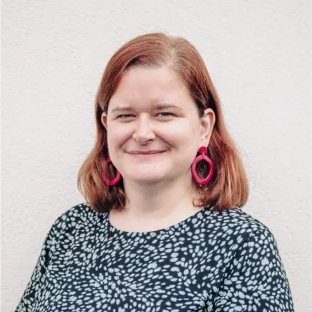 Woman with red hair and pink earrings and spotty top