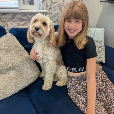 A girl cuddles a dog on a sofa.