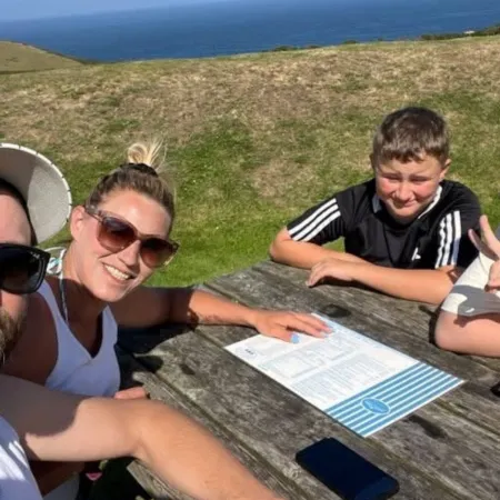 A family sit at a bench by the ocean.