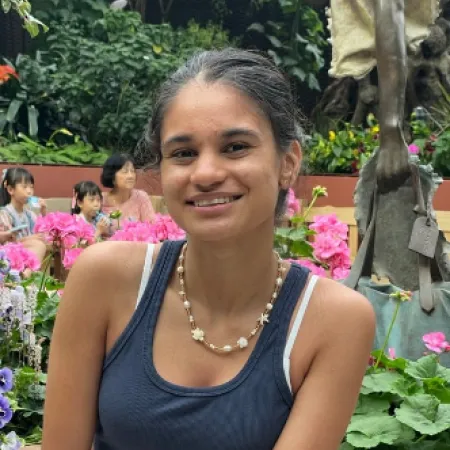 A young woman smiles before a blooming garden.
