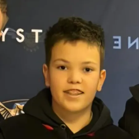 A young man smiles in front of a step-and-repeat.