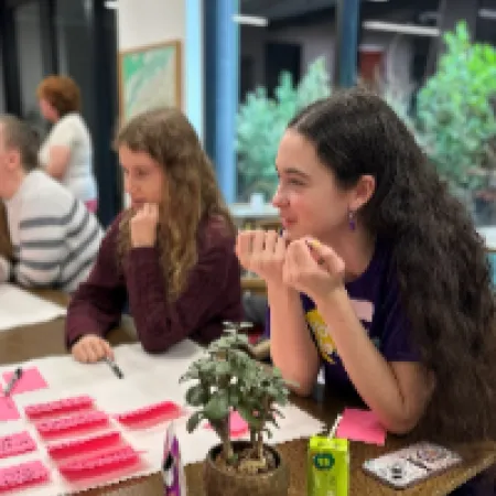 A group of young adults sit at a desk brainstorming ideas.