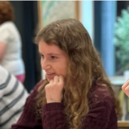 A young woman sits a desk with her peers.