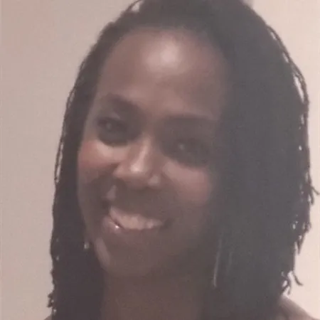 A woman against a white background smiles to camera.