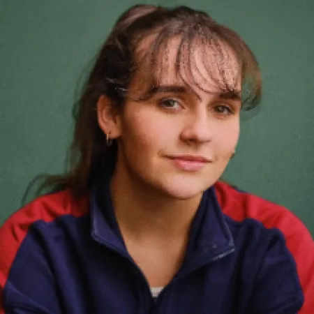 A woman smiles against a green background.