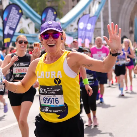 London Marathon Runner smiles and waves with a purple cap