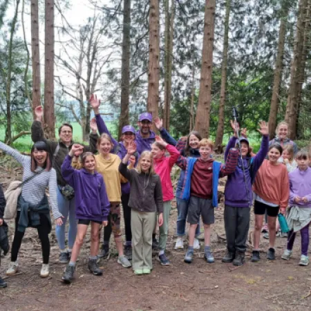 A group of hikers celebrate in a forest.