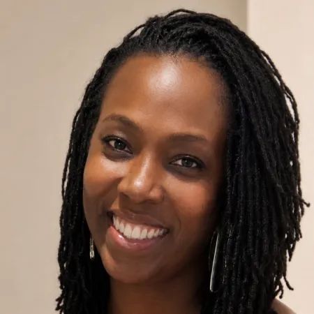 A woman against a white background smiles to camera.