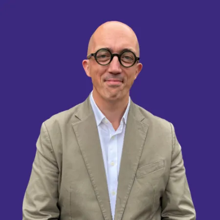 Ben Bastin stands in front of a blue background.