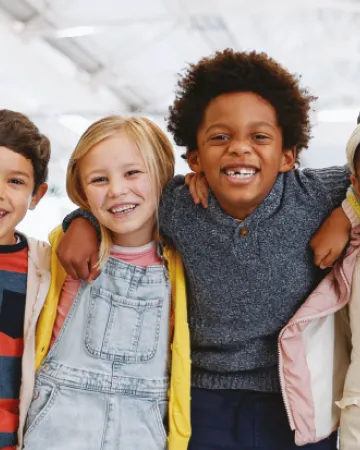 A group of young children smile while holding shoulders on the cover of a Young Epilepsy research report.