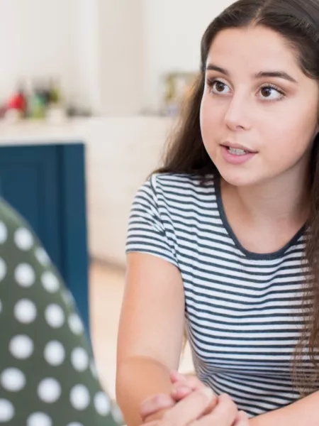 A young woman has a deep conversation with another woman across a table.