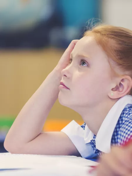 A school student looks toward the front of the classroom concentrating.