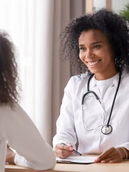 A medical professional smiles at a younger patient during a consultation.