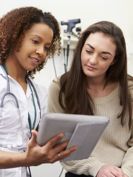 A doctor shows a young woman information in a medical consultation.