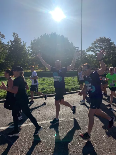 Two men in young epilepsy tops waving as they run by