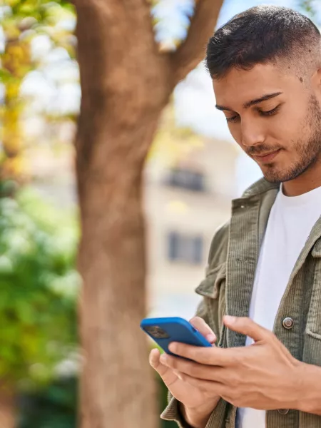 Young boy smiling confident using smartphone at park