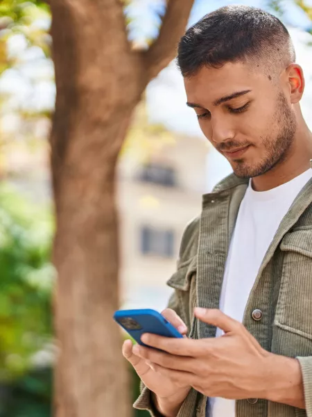 Young boy smiling confident using smartphone at park