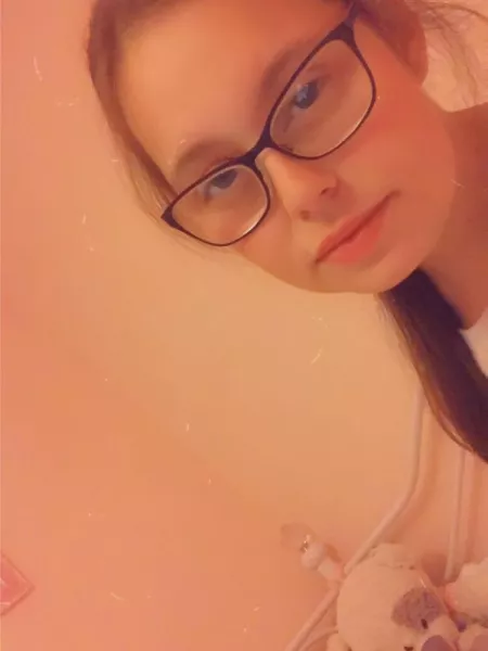 A young woman in glasses looks into the camera for a selfie.