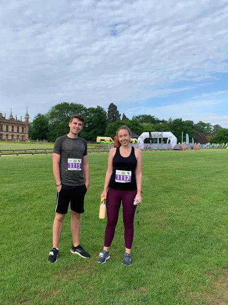 A man and woman representing Young Epilepsy at a sporting event smile in a field.