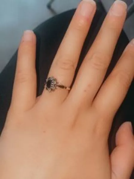A woman's hand reveals an engagement ring with a black stone.