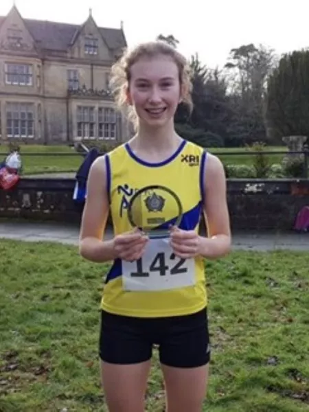A runner shows off her trophy on a summer's day.