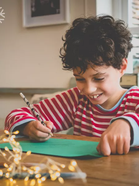 A young boy writes a Christmas list.