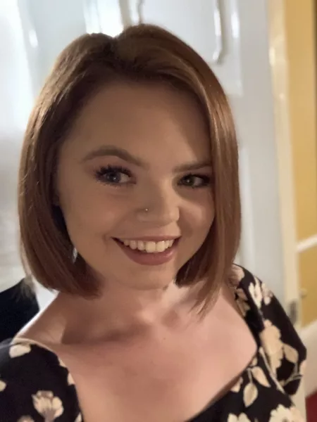 A young woman with a bob smiles widely into the camera.