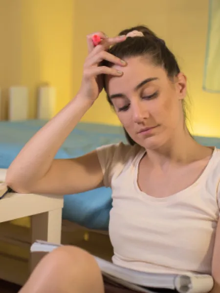 Young girl sitting on the floor, revising for exams with head in hands