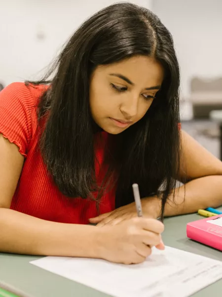 Young girl writing on an exam paper in an exam hall
