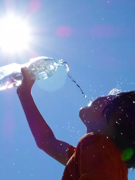 young child pours water from a bottle in the hot sun