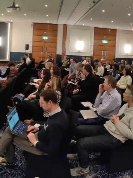 A large group of researchers listen to a lecturer using slides at a research retreat with Young Epilepsy.