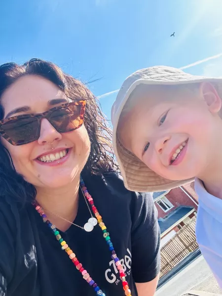 A mother and her sun smile in a selfie under a blue sky.